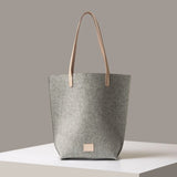 Gray tote bag with beige handle on a neutral background