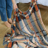 Person holding a plaid blanket on a wooden floor
