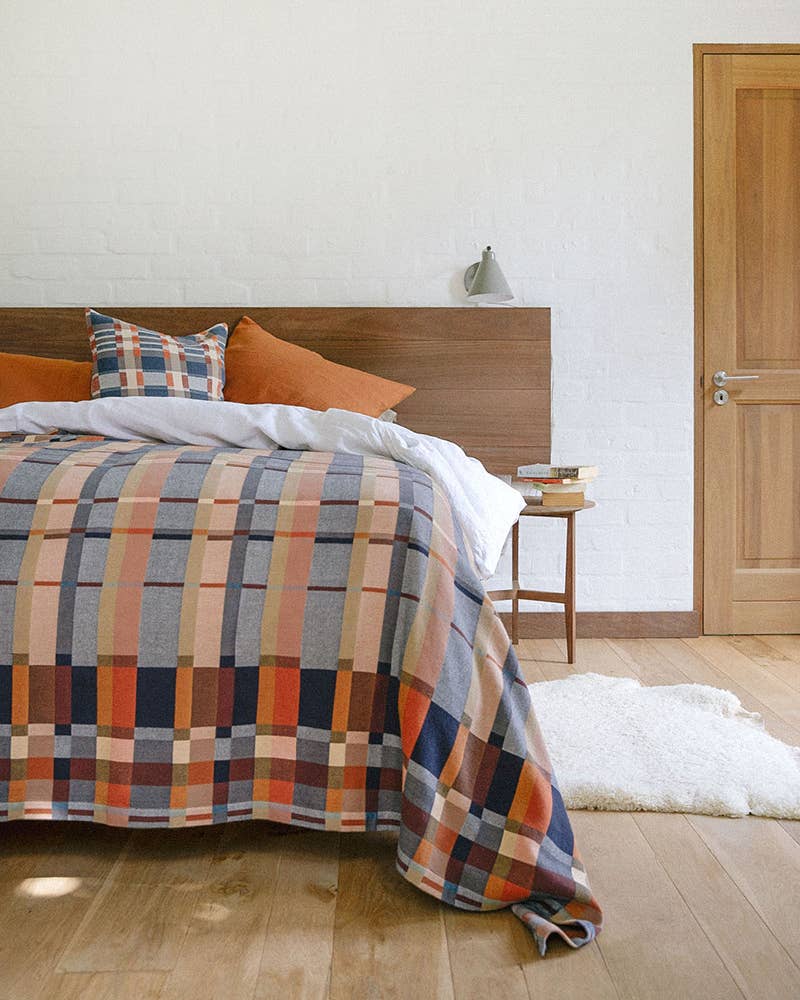 Bed with plaid comforter and pillows in a bedroom setting.