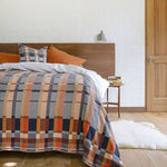 Bed with plaid comforter and pillows in a bedroom setting.