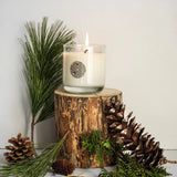 Candle on a wooden stump with pine cones and branches on a light background