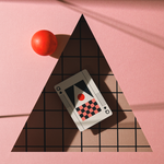 Card with a checkered design and red ball on a pink surface with a triangular shadow