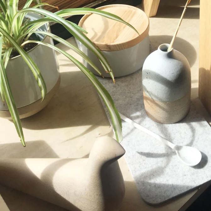 Decorative items on a table including a plant, ceramic vase, and mug.