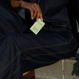Person holding a green Noshinku sprayer against a dark denim background