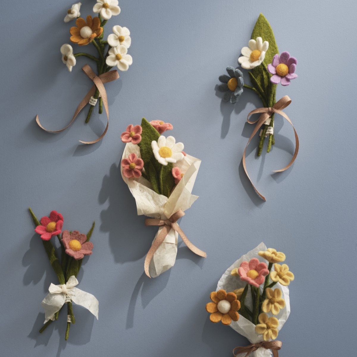 Set of felt flower bouquets and ribbons on a gray background