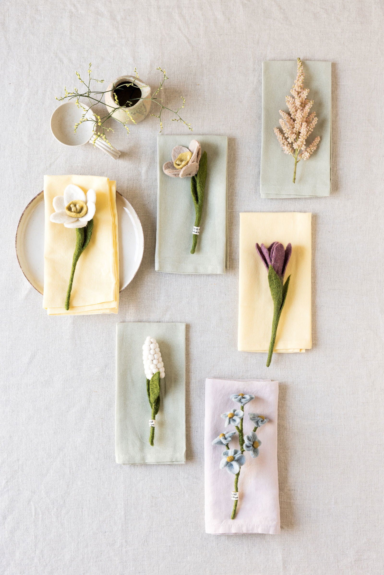 Felt flowers displayed on napkins against a light beige tablecloth