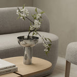 Silver bowl with white flowers on a wooden table in a living room setting.