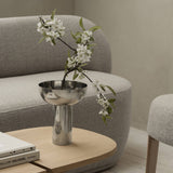 Silver bowl with white flowers on a wooden table in a living room setting.