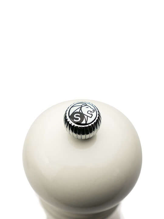 Top of white salt mill with a metallic cap featuring Peugeot lion logo on a white background
