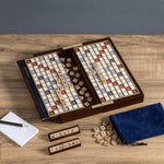 Travel Scrabble game board unfolded and open on a wooden table with tiles and pieces.