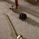 Decorative elements including a candle, pinecones, and a candle holder on a textured surface.