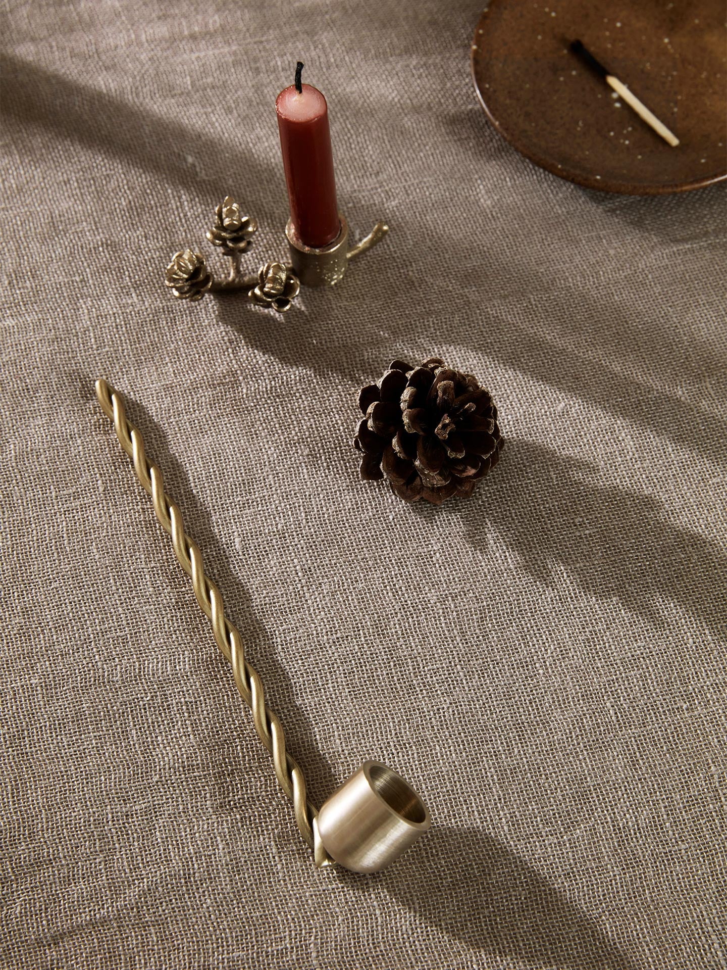 Decorative elements including a candle, pinecones, and a candle holder on a textured surface.