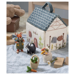 A felted wool house with a blue roof, designed for imaginative play. The house is open, revealing a charming interior with embroidered details.