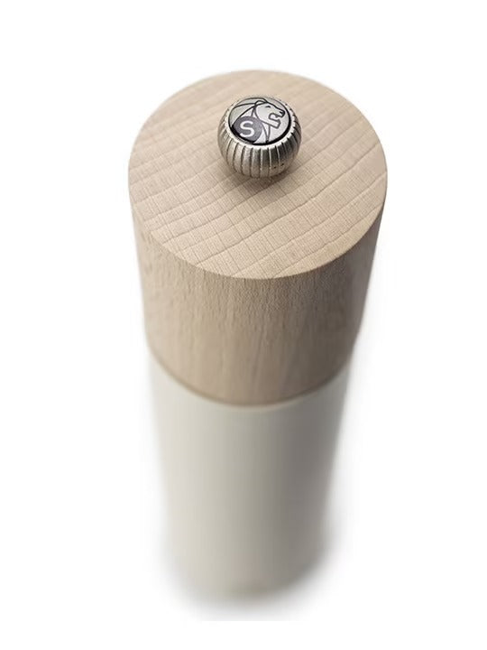 White salt grinder with a wood top with metal logo button on a white background