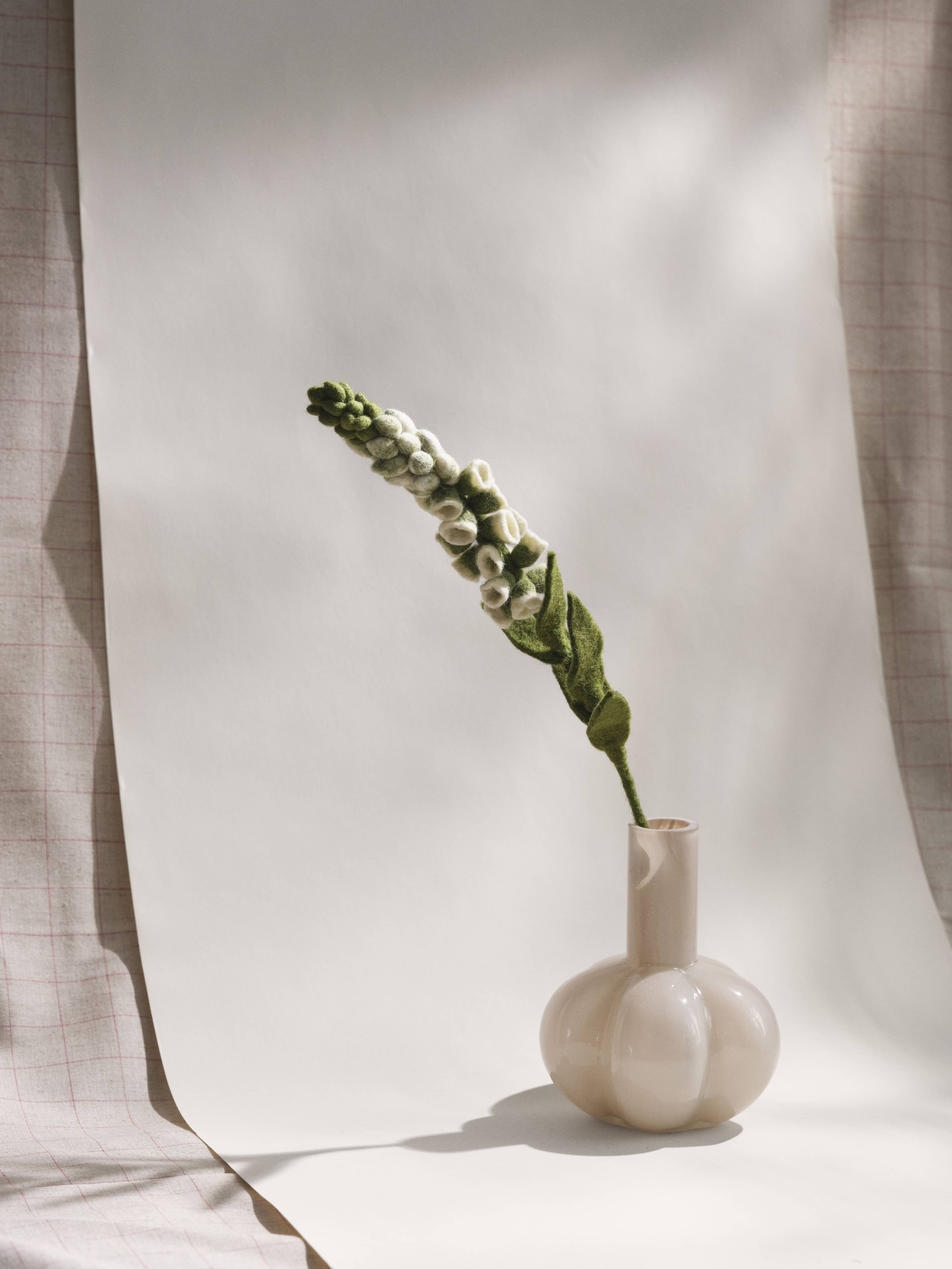 Small vase with a single flower stem against a neutral background