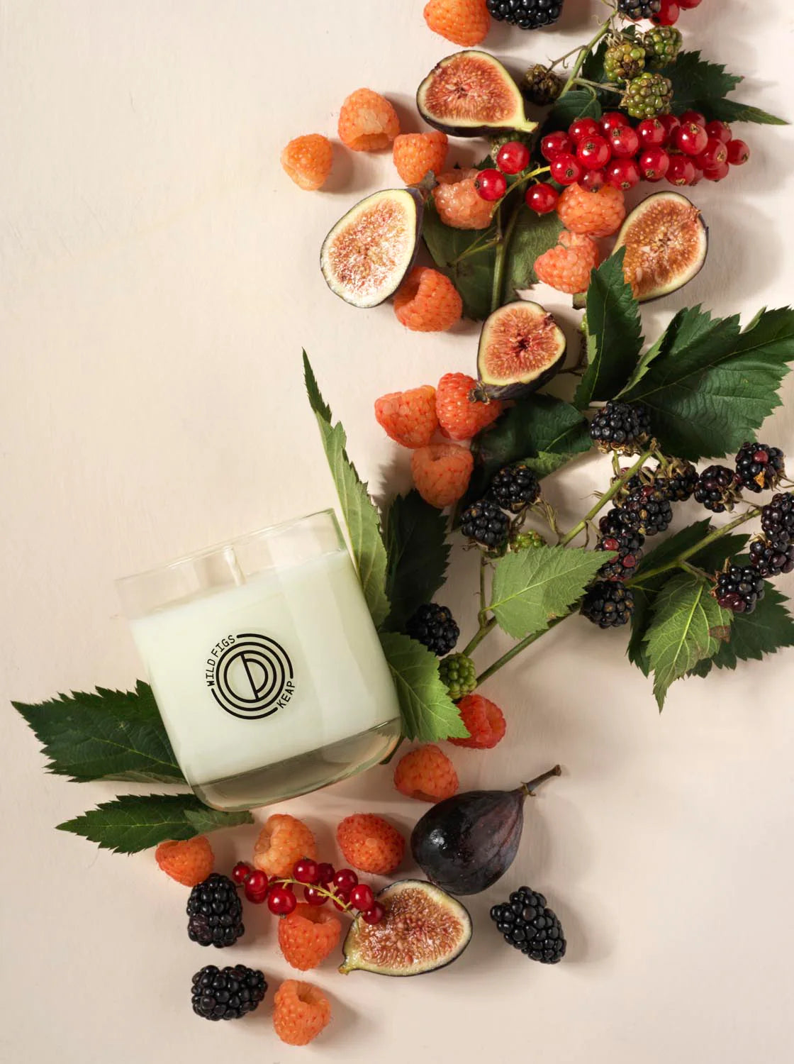 Candle with a fruit and leaf arrangement on a light background