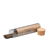 Incense sticks in a cylindrical glass holder with cork lid on a white background