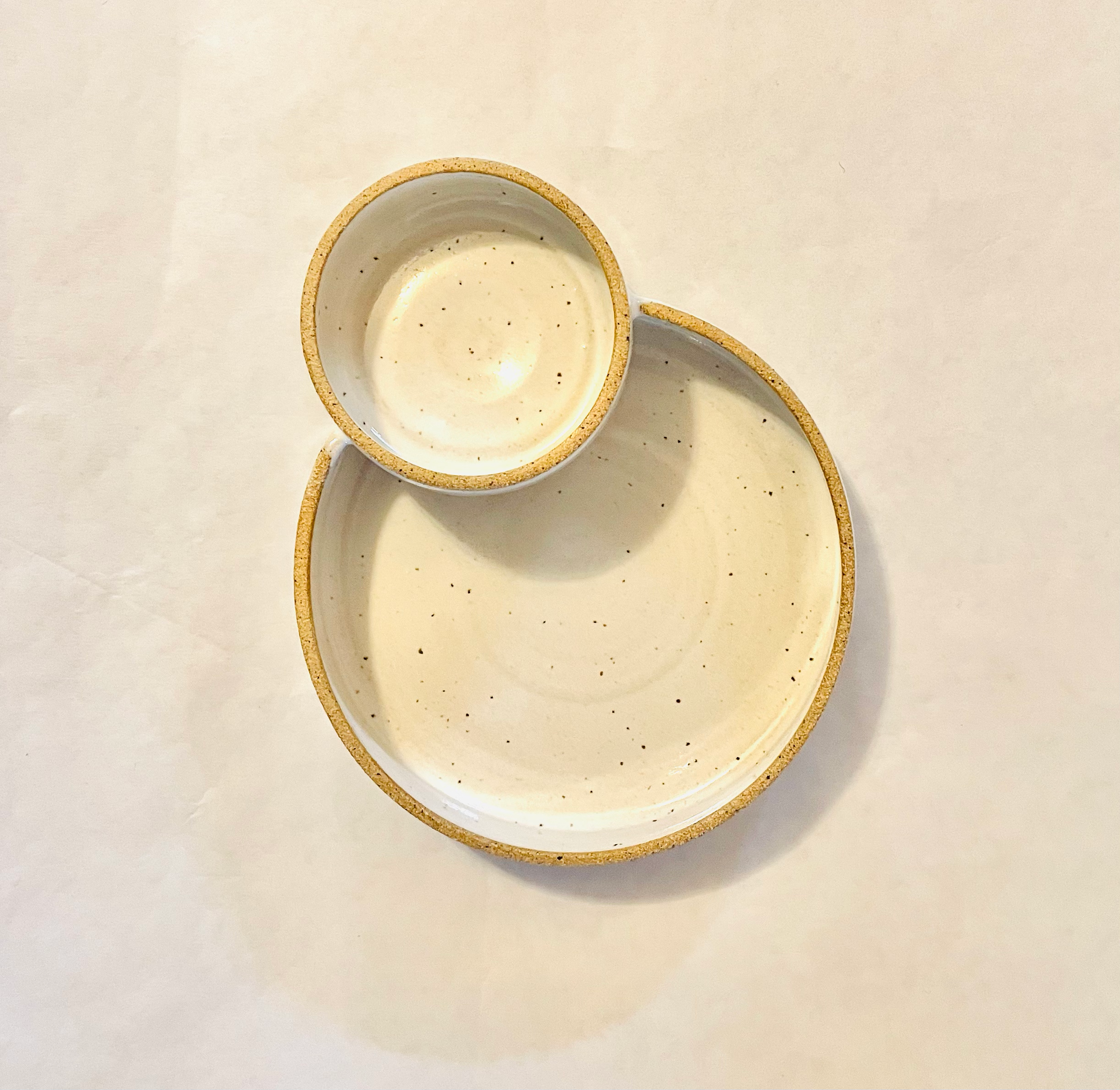 Ceramic speckled serving bowl with a smaller bowl attached, displayed on a plain background.