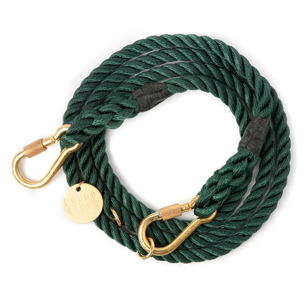 Hunter green Adjustable Rope Leash is coiled in a circle, with each end ending in a carabiner style brass clip that rests on top of the coil.