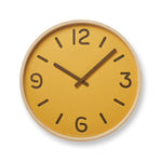 A yellow wall clock with a wooden frame and paper face, designed by Yuichi Nara.